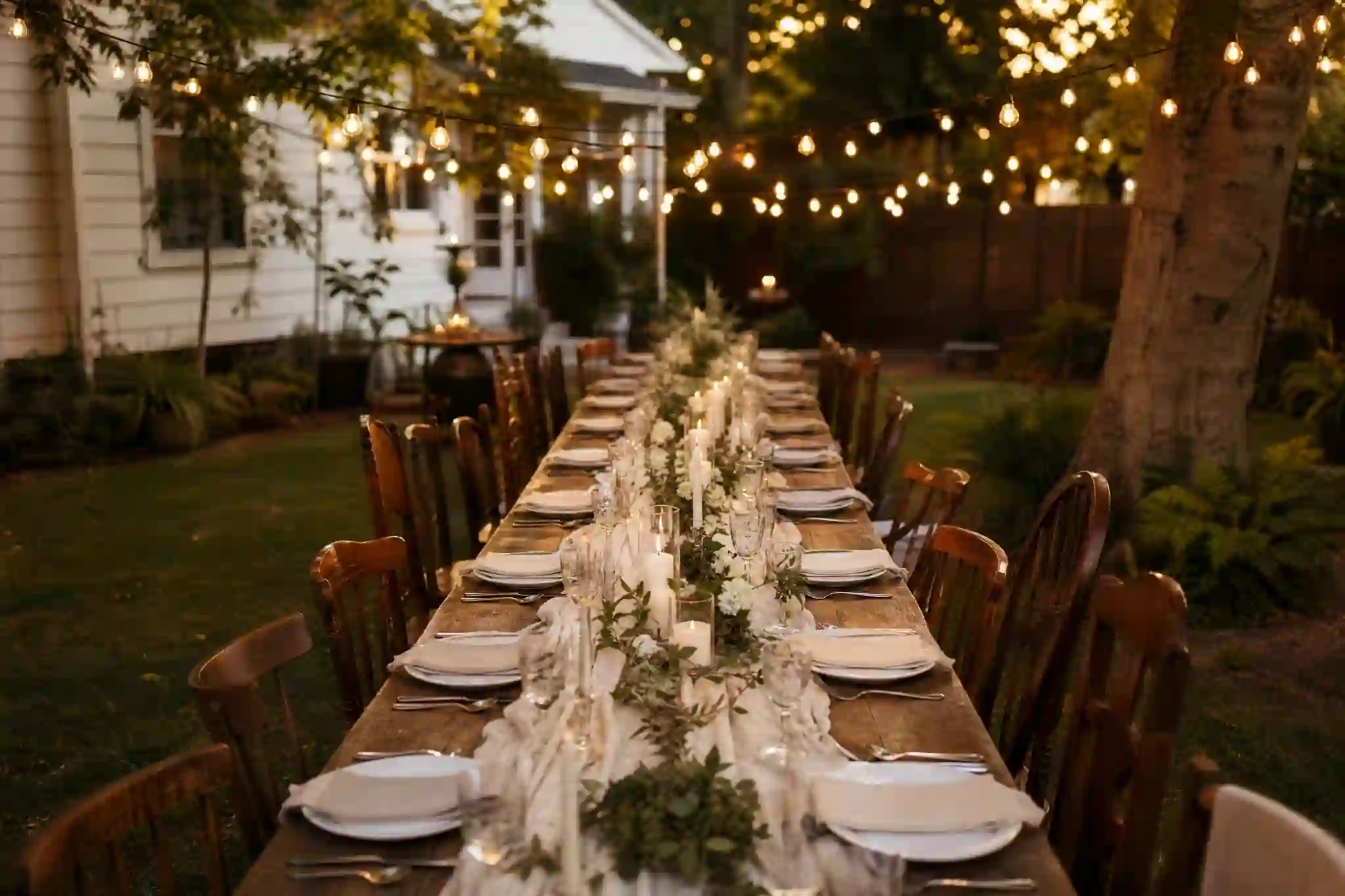 small backyard wedding ideas with string lights and long table,cozy small backyard wedding ideas with mismatched chairs and florals,budget-friendly small backyard wedding ideas table setup